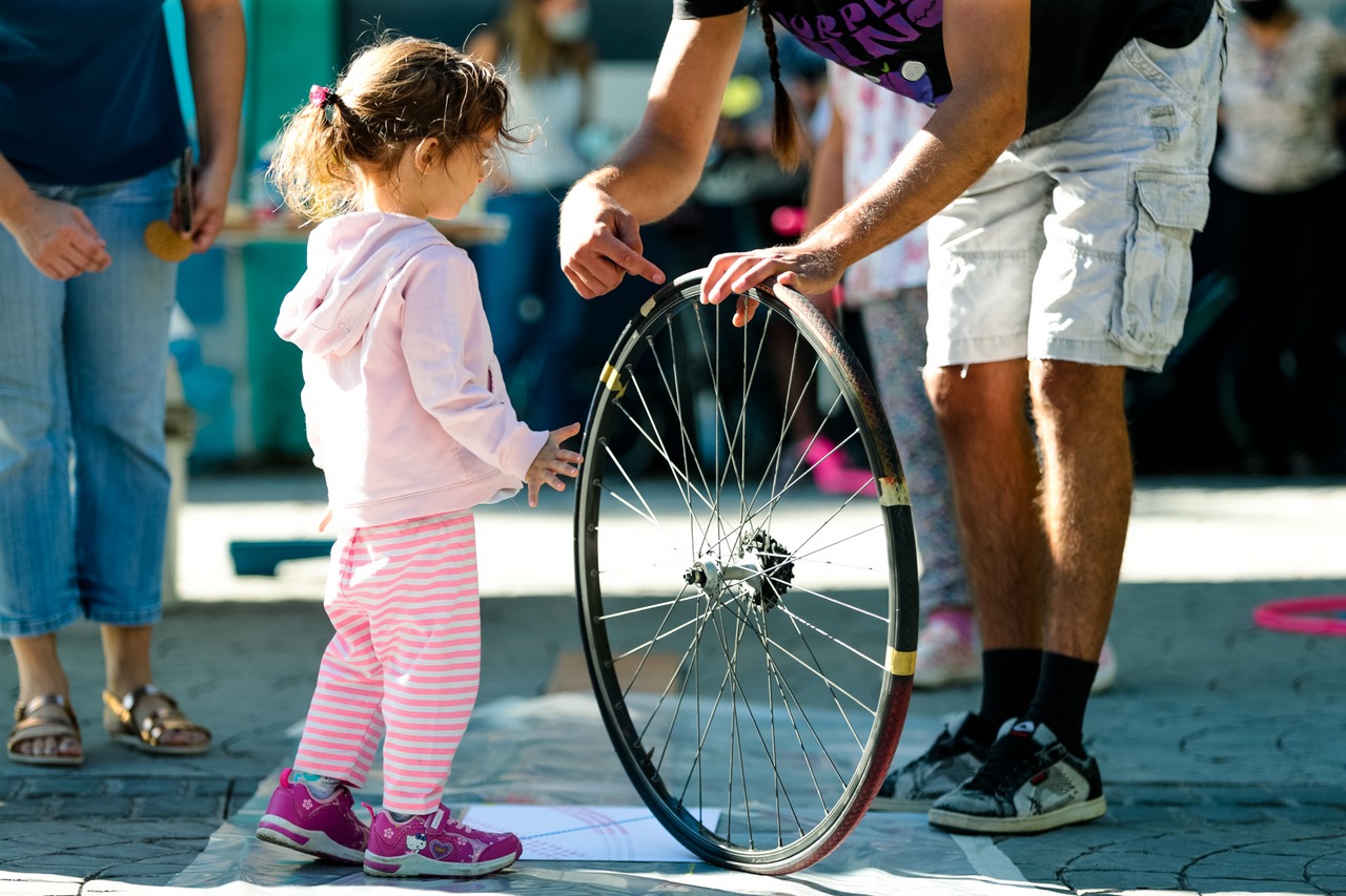 Τυπώματα με ποδήλατο - Ένας άντρας δείχνει μία μεγάλη ρόδα σε ένα κορίτσι