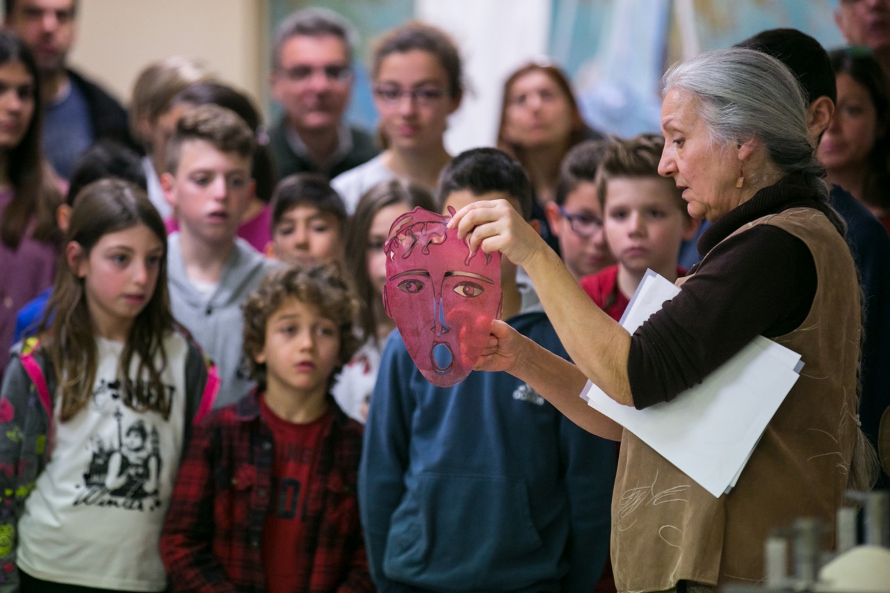 Χαρακτική στο Μουσείο - Γυναίκα δείχνει χάρτινη φιγούρα σε παιδιά